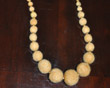 Long strand of graduated-size yellow felt beads with gold fresh water pearls